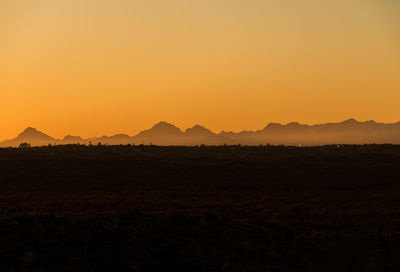 Scenic view of silhouette field against sky during sunset