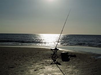 Fishing rod on beach against sky