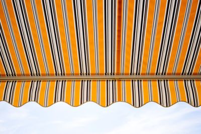 Low angle view of striped awning against sky