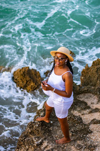 Rear view of woman standing on rock at beach