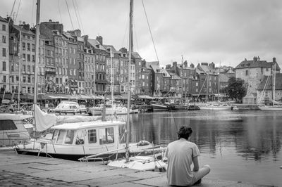 Rear view of man in river against buildings in city