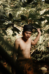 Portrait of young man standing against plants