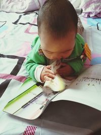 High angle view of cute baby sitting on bed at home