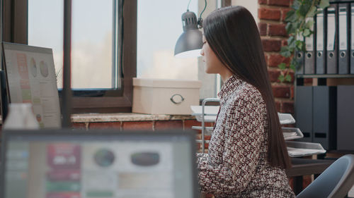 Side view of woman sitting at office