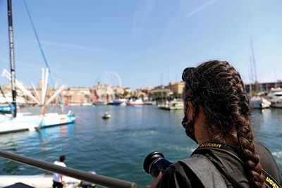 Rear view of man in sea against cityscape