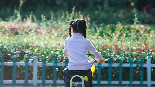 Rear view of girl cycling against plants