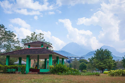 House by trees and mountains against sky