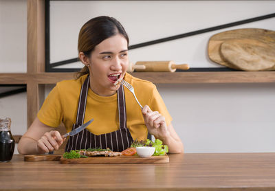 Portrait of woman holding ice cream on table
