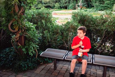 Boy sitting on bench in park