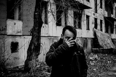 Front view of young man standing against abandoned built structure