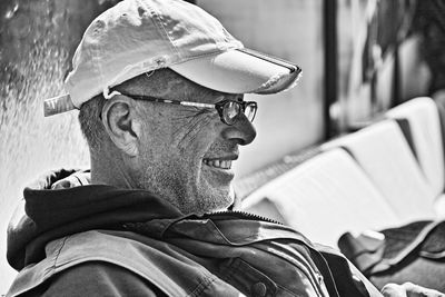 Smiling senior man wearing cap sitting on bench