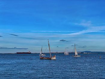 Sailboats sailing in sea against blue sky