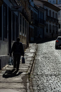 Rear view of man walking on street amidst buildings