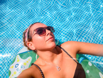 High angle view of woman relaxing on inflatable raft at swimming pool