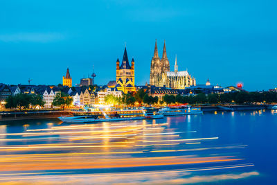 High angle view of light trails on river in city against blue sky