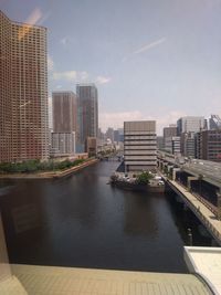 Buildings by river against sky in city