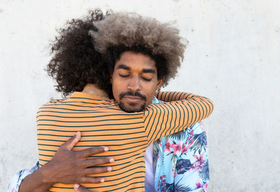 Portrait of young man standing against wall