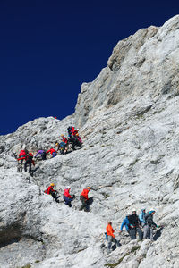 Low angle view of hikers hiking on rocky mountain