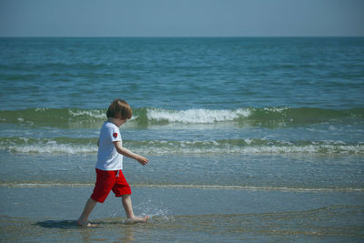 Full length of boy on beach against sea