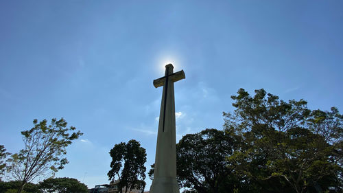 Low angle view of cross against trees against sky