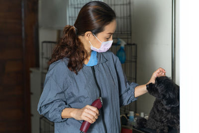 Woman grooming black dog at home