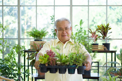 Portrait of man holding potted plants