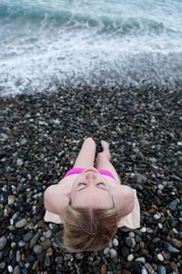High angle view of teenage girl relaxing at pebbles covered beach