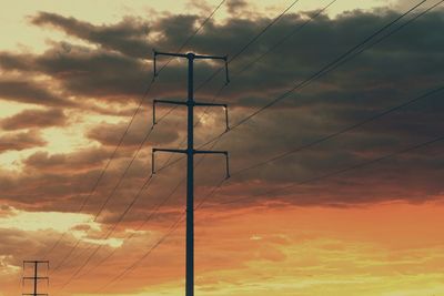 Low angle view of power lines against cloudy sky