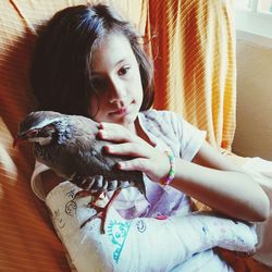 Bird perching on fractured arm of girl in bed