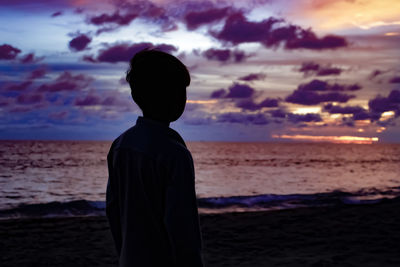 Silhouette man on beach against sky during sunset