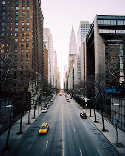 Traffic on road amidst buildings in city against sky