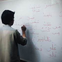 Rear view of man writing on whiteboard