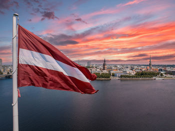 Latvian flag with the dome cathedral and an old town in the background