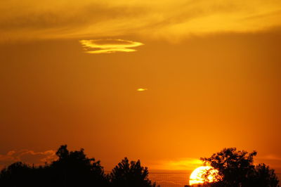 Silhouette trees against dramatic sky during sunset