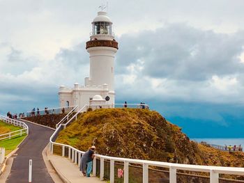 View of lighthouse in sea against cloudy sky