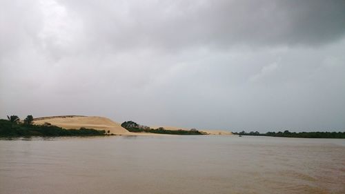 Scenic view of river against cloudy sky