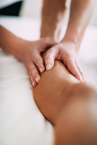 Cropped hands of massage therapist massaging female customer leg in spa