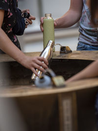 Midsection of women filling water in bottle