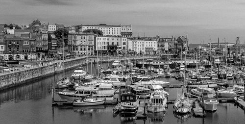 High angle view of boats moored at harbor against buildings in city