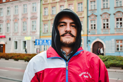 Portrait of young man standing against building in city