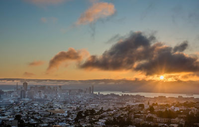 Aerial view of buildings against cloudy sky at sunset