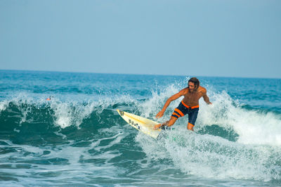 Man surfing on sea against clear sky