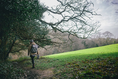 Rear view of woman walking on pathway by trees at forest