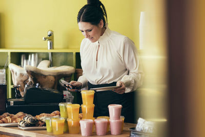 Waitress serving croissant to customer in coffee shop