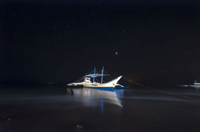 Boats in calm sea at night