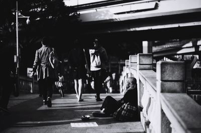 Beggar sitting on footbridge in city