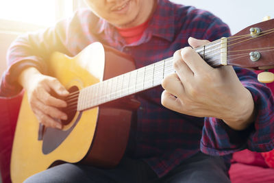 Midsection of man playing guitar