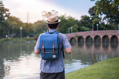 Rear view of man standing on bridge over river