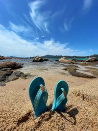 Panoramic view of shoes on beach against blue sky