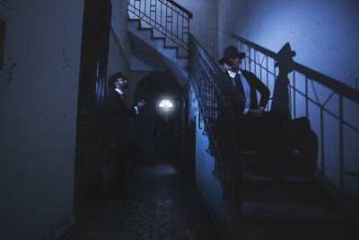 Men by staircase in darkroom